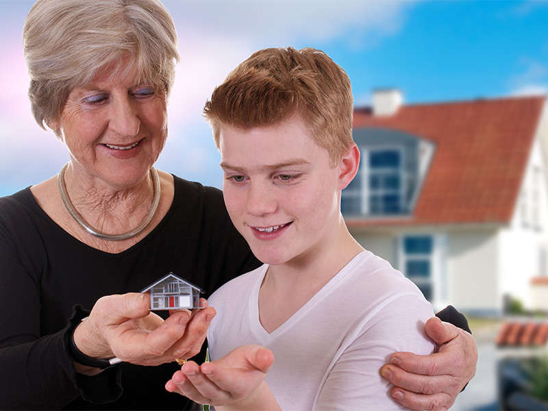 Großmutter übergibt ihrem Enkel symbolisch ein Haus und thematisiert die Immobilienübertragung sowie das Vererben einer Immobilie in Lörrach.