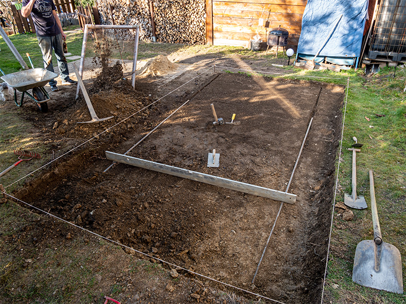 Vorbereitete Gartenfläche mit ausgehobenem Erdboden für die Planung und Umsetzung eines individuellen Poolprojekts im Außenbereich.
